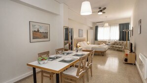 Une chambre d’hôtel avec un coin repas, un canapé et un fauteuil.