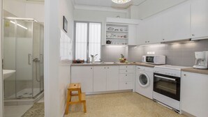 Une cuisine moderne avec des meubles blancs, un lave-linge, un four à micro-ondes et une machine à café.