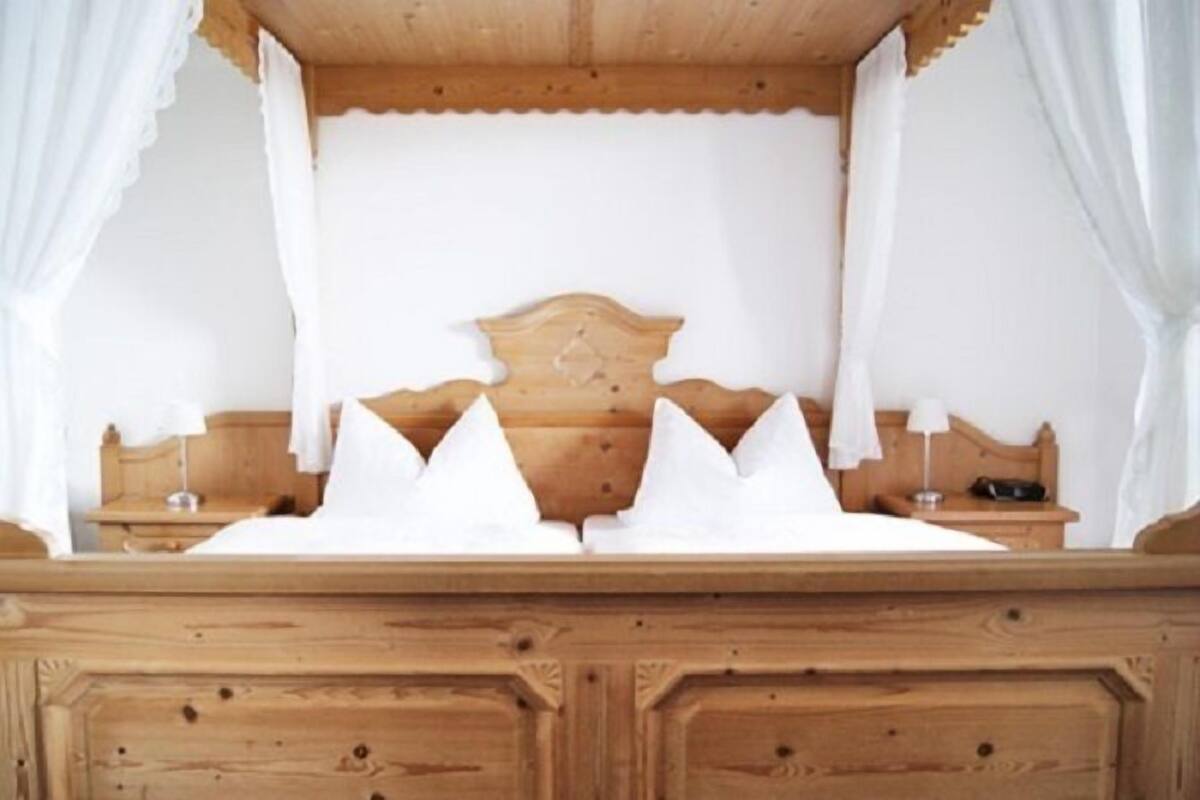 Una cama de madera con dosel, dos mesitas de noche y un buró.