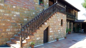 A stone building with a wooden staircase and a balcony. - Posada La Vieja Escuela (San Vicente de la Barquera)