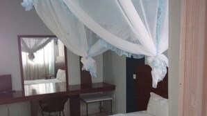 Un dormitorio con cama, escritorio, silla y espejo.