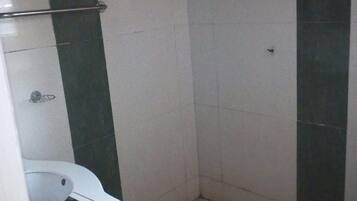 Un baño con un lavamanos blanco, una ducha con azulejos verdes y una lámpara de techo blanca.