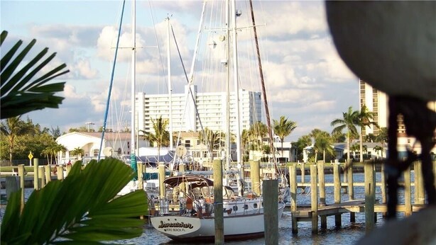 A marina with boats docked, a building in the background, and palm trees. - Walk to the Beach at Nettles Island 4 bed/2 bath sleeps 8 (Jensen Beach)