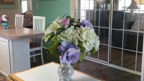 A room with teal walls, a white table with a vase of flowers, and a sign reading "BEACH HOUSE". - Walk to the Beach at Nettles Island 4 bed/2 bath sleeps 8 (Jensen Beach)