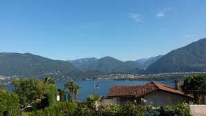Une vue côtière avec des montagnes, un lac et un petit bâtiment doté d’un toit rouge.