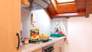 Une cuisine avec des meubles de rangement en bois, un four encastré et une fenêtre au-dessus de l’évier.