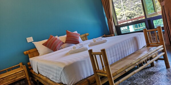 A bed with white bedding, red patterned pillows, and a wooden headboard.