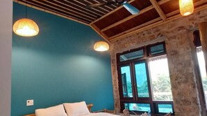 A bedroom with a bed, two hanging lamps, a ceiling fan, and a large window with a view. - Trang An Ecolodge (Tay Hoa Lu)