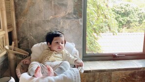 A child lying in a white cushioned chair by a window with a view of greenery outside. - Trang An Ecolodge (Tay Hoa Lu)