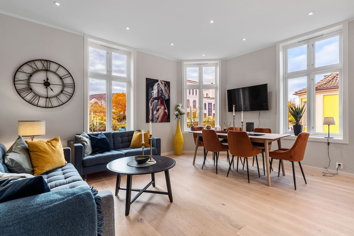 A modern living room with a sofa, coffee table, and dining area with chairs and a TV.