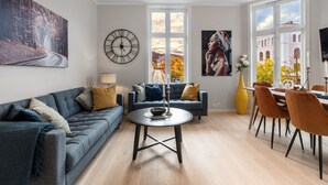 A modern living room with a sofa, a coffee table, and a dining area with chairs and a table.