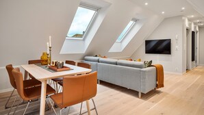 A modern loft apartment with a dining area, sofa, and TV.