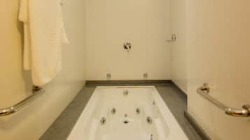 A modern bathroom with a large bathtub, grab bars, and a towel rack.