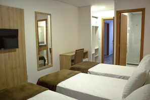 Habitación de hotel con dos camas, un escritorio, una silla, un televisor y un espejo.