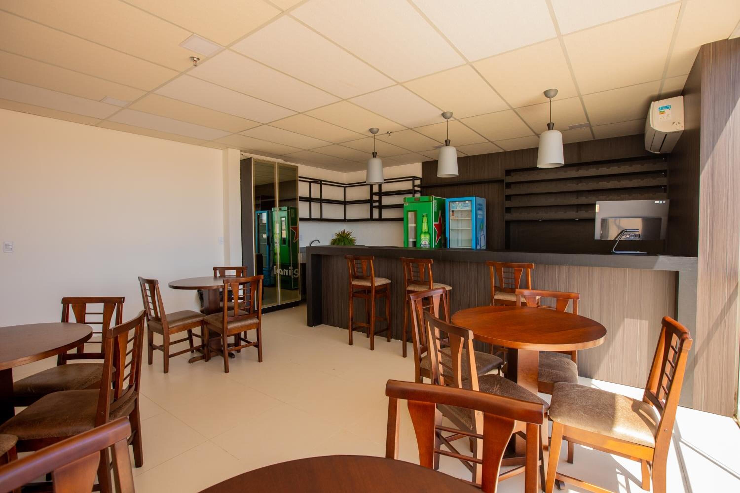 A modern dining area with wooden tables and chairs, a counter with a menu display, and pendant lighting.