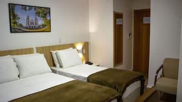 A hotel room with two beds, a chair, and a painting on the wall.