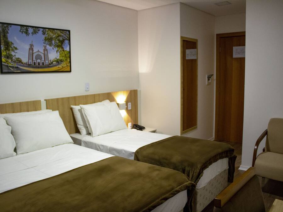 A hotel room with two beds, a chair, and a painting on the wall.