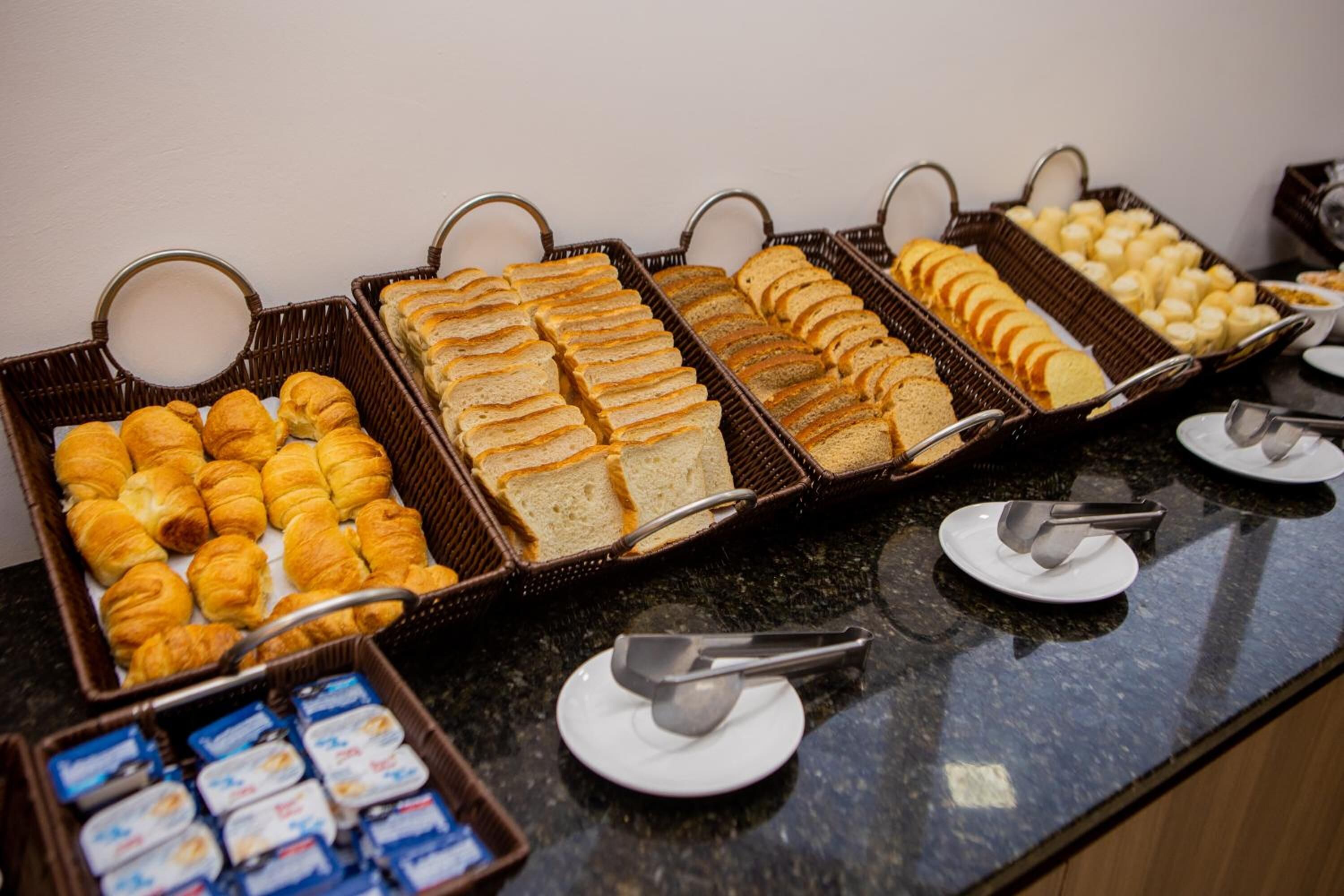 Un buffet proposant une variété d’aliments, notamment du pain, des pâtisseries et des produits laitiers.