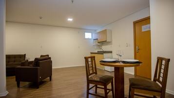 Um espaço compacto com área de jantar, cozinha compacta e sala de estar com sofá e cadeiras.