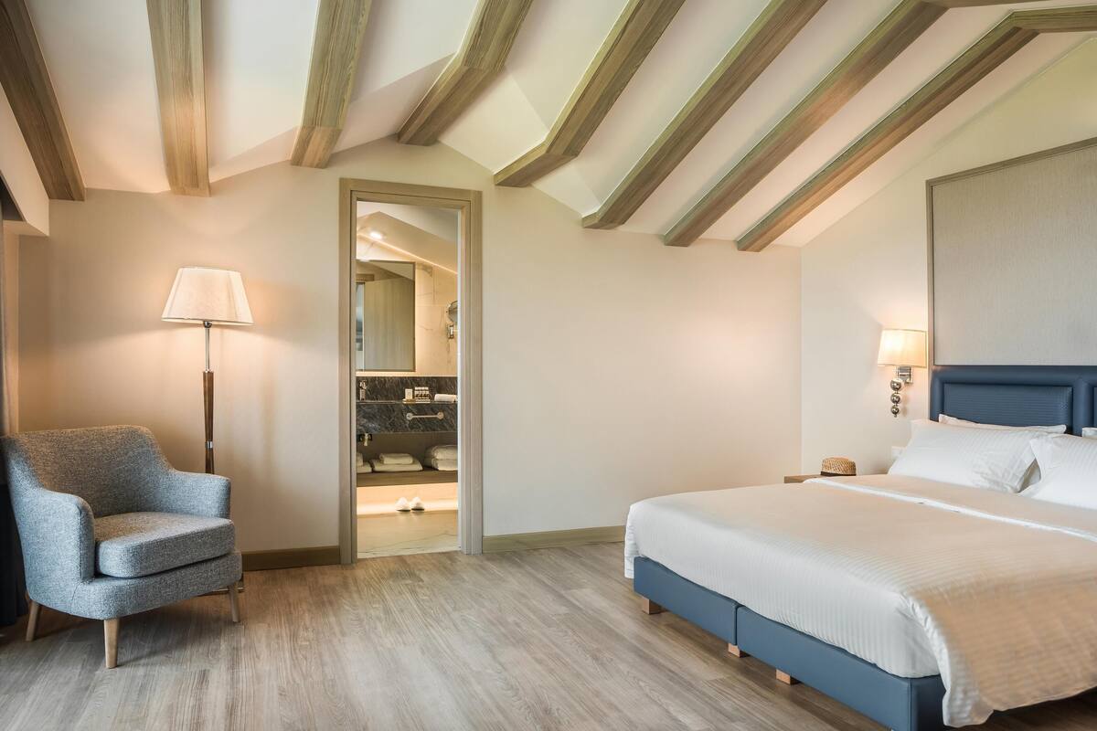 Een slaapkamer met een bed, een stoel en een lamp.
