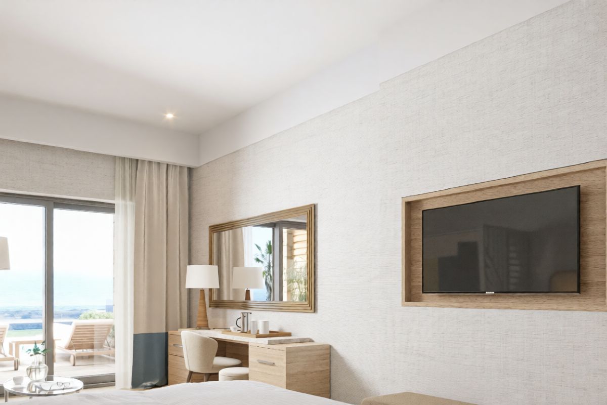A hotel room with a bed, a desk, a chair, a TV, and a large window offering a view.