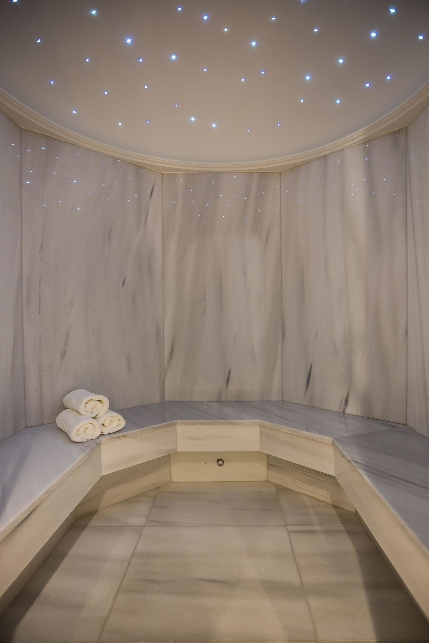 A spa room with a curved bench, a towel, and a ceiling with small lights.