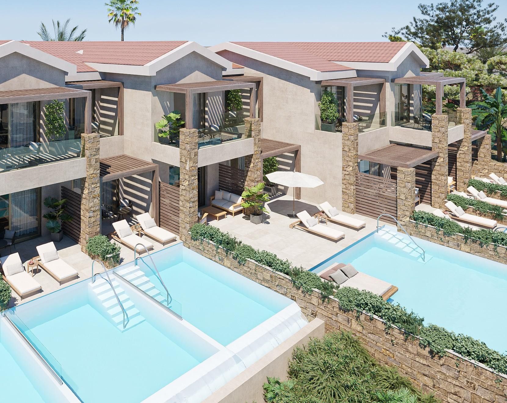 A modern resort with multiple swimming pools, sun loungers, and a stone facade.