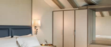 Een hotelkamer met een groot bed, een nachtkastje met een lamp, een kledingkast en een spiegel.