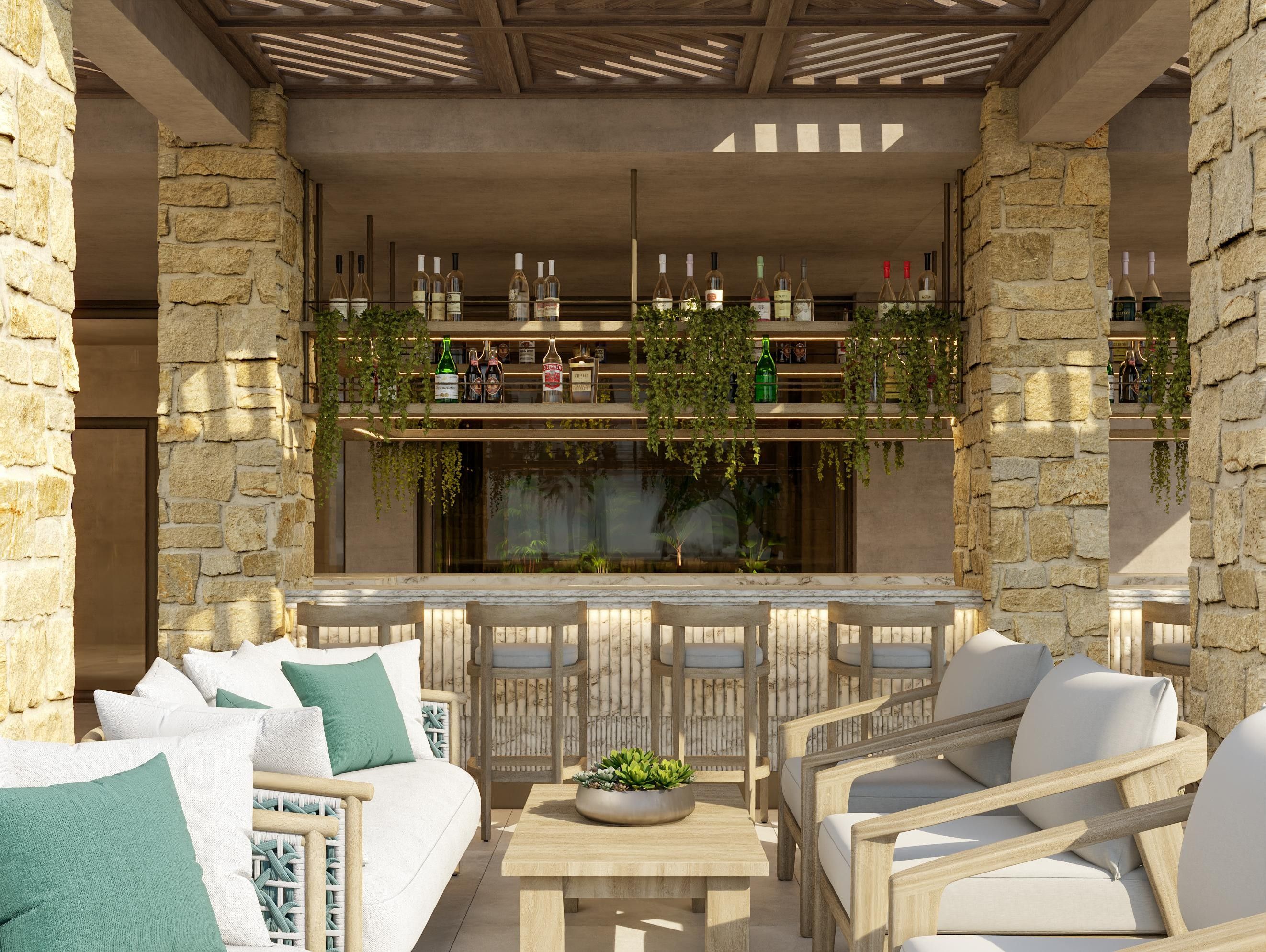 An outdoor seating area with stone walls, a bar with wine bottles, and a view of the interior.