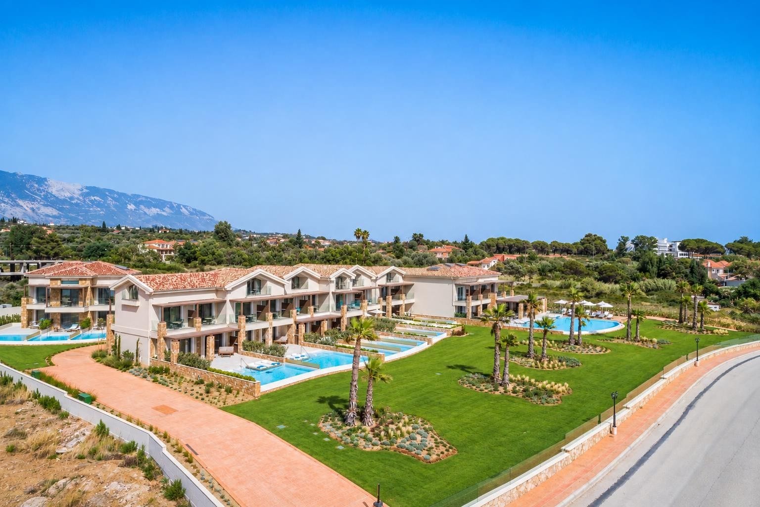 Un hôtel à plusieurs étages doté d’une piscine et de jardins aménagés.