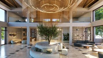 Eine geräumige Lobby mit einer zentralen Sitzecke, einem großen Baum und einem modernen Deckenstil.