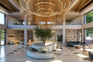 Eine geräumige Lobby mit einer zentralen Sitzecke, einem großen Baum und einem modernen Deckenstil.