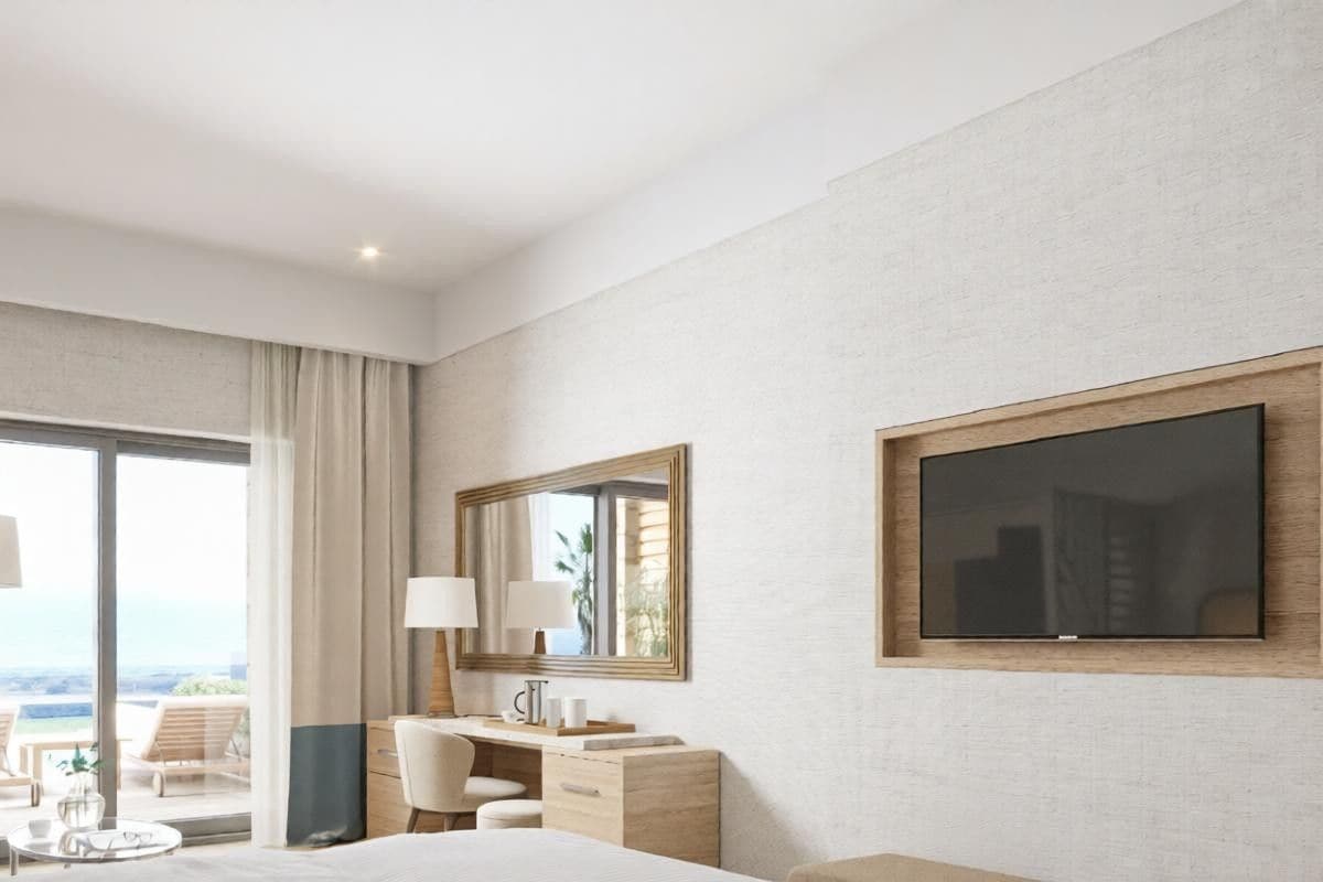 Ein Hotelzimmer mit einem Bett, einem Schreibtisch, einem Sessel, einem Fernseher und einem großen Fenster mit Blick.