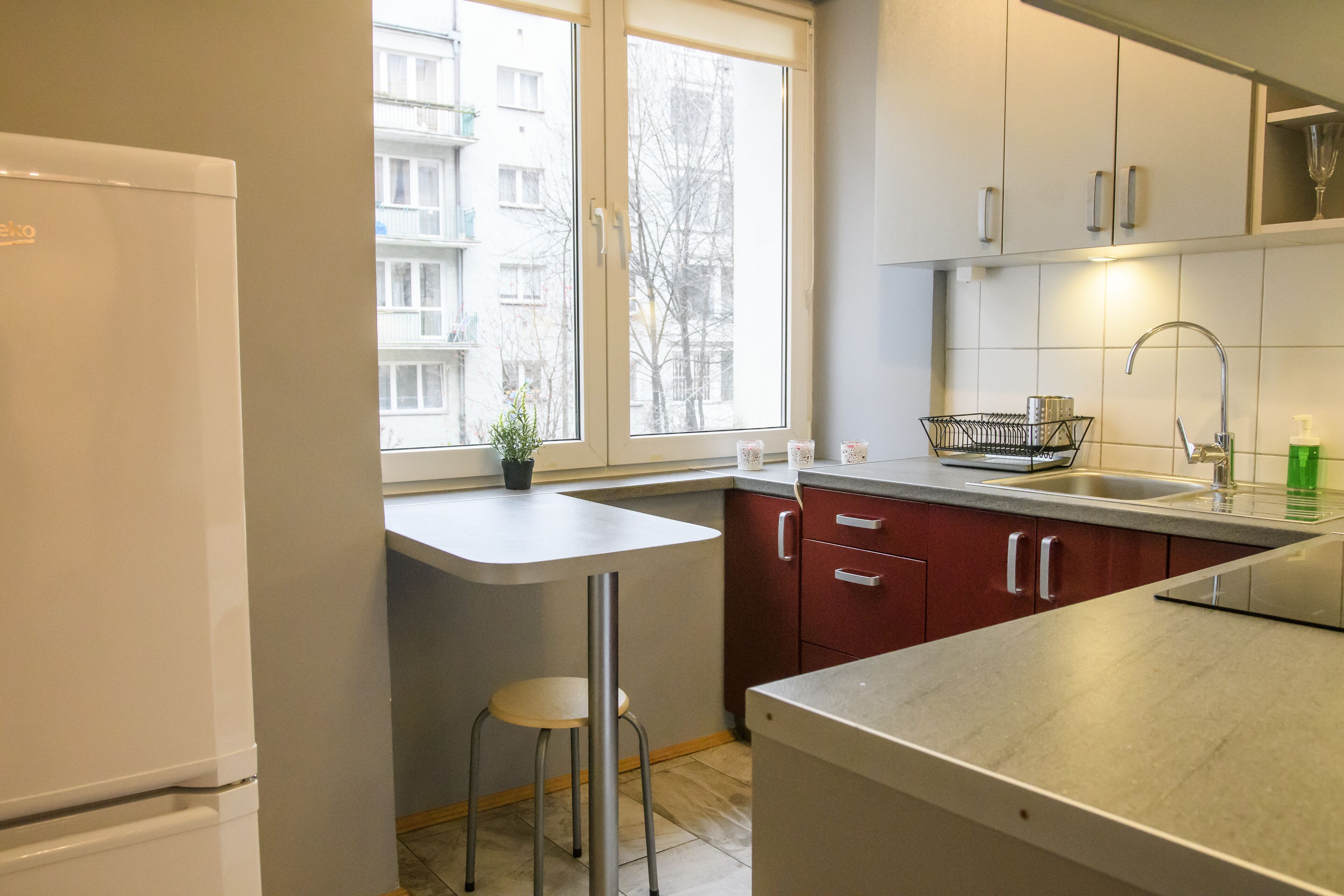 A modern kitchen with a built-in refrigerator, a window with a view of a building, and a bar stool.