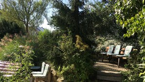 Un jardín con una escalera de piedra que lleva a una zona de estar con sillas.