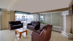 A spacious living area with two leather sofas, a wooden coffee table, and a large window with blinds. - Hotel San Pablo (San Pedro Cholula)