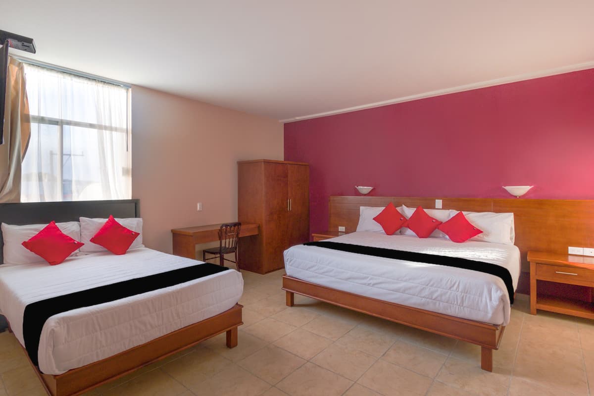 A hotel room with two beds, a desk, a chair, and a wardrobe.
