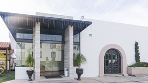 A modern building with a glass entrance, large columns, and a covered entrance area. - Hotel San Pablo (San Pedro Cholula)