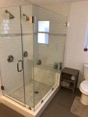 A glass-enclosed shower with a tiled floor and a glass door.