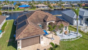 A residential property with a large garage, a swimming pool, and a dock extending into a body of water. - Wonderful New 3 Bedroom Villa , with direct Gluf Acces for your holidays (CAPE CORAL)