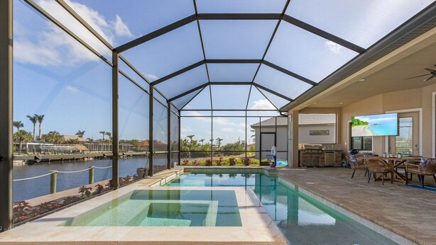 A covered outdoor swimming pool with a view of the marina and palm trees. - Wonderful New 3 Bedroom Villa , with direct Gluf Acces for your holidays (CAPE CORAL)