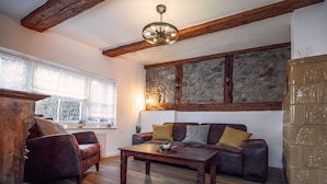 A cozy living room with a leather sofa, wooden coffee table, and a stone wall. - Gesindehaus Börnecke (Blankenburg)