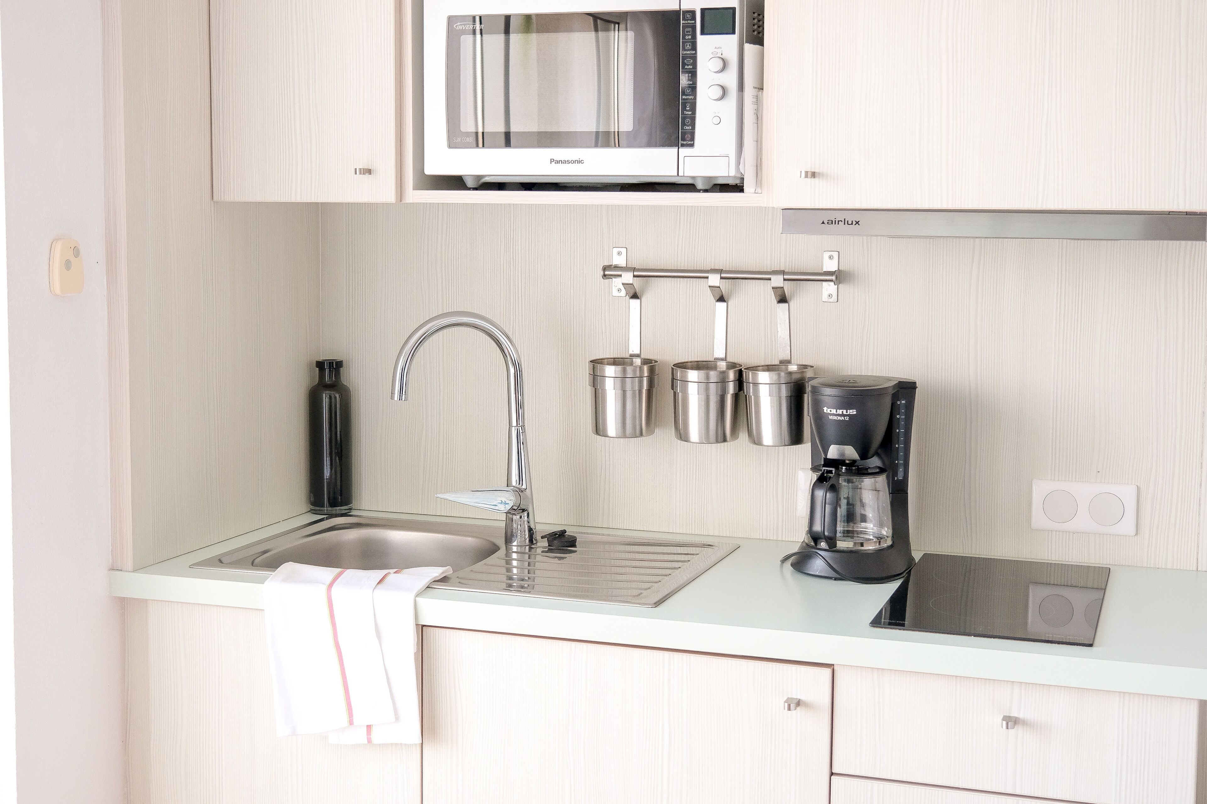 Una cucina moderna con forno a microonde integrato, lavello in acciaio inossidabile e macchina da caffè.