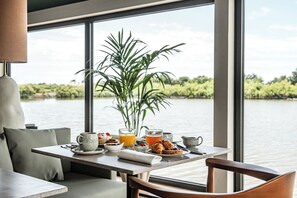 A dining table with breakfast items, a plant, and a view of a lake. - Thalazur Carnac - Résidence (Carnac)