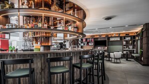 A modern bar area with wooden bar counters, multiple seating options, and a variety of bottles and glasses on shelves. - Thalazur Carnac - Résidence (Carnac)