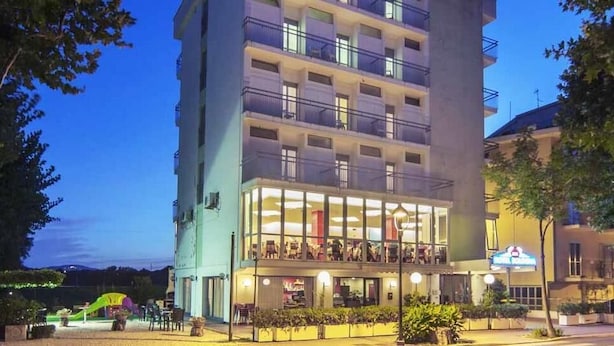 A multi-story hotel with a ground-level restaurant and outdoor seating. - Hotel Bologna (Misano Adriatico)