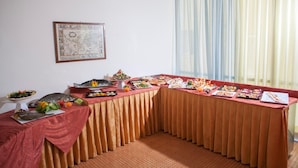 A buffet table with various dishes, a framed map on the wall, and a window with curtains. - Hotel Bologna (Misano Adriatico)