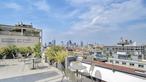 Terraza en la azotea con mobiliario exterior y vistas al horizonte urbano.