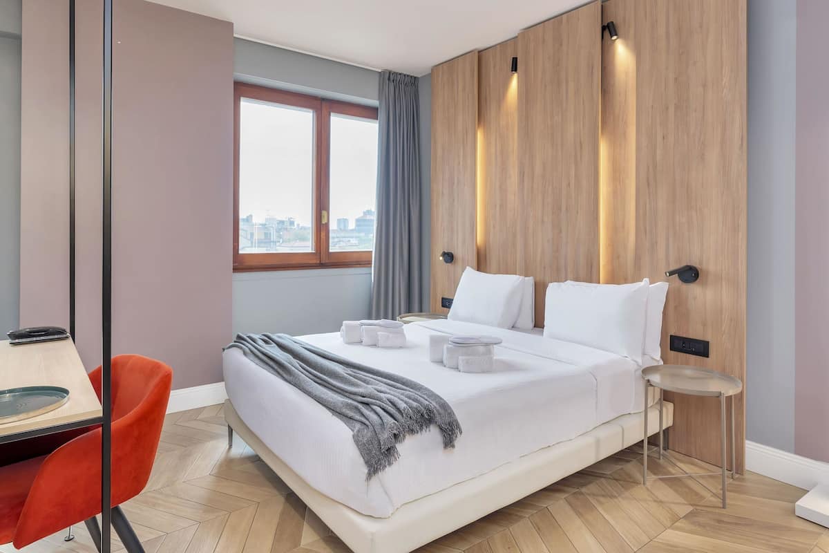 Ett modernt hotellrum med en stor säng, ett skrivbord och en stol.