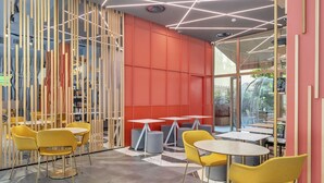 Un interior moderno con sillas y mesas amarillas, una pared roja y un diseño geométrico en el techo.